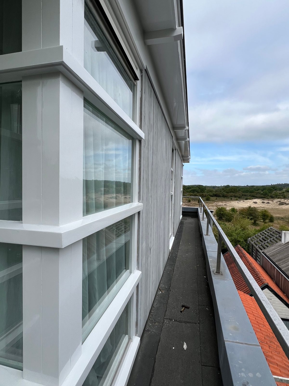 Witte kozijnen op balkon met uitzicht over de duinen